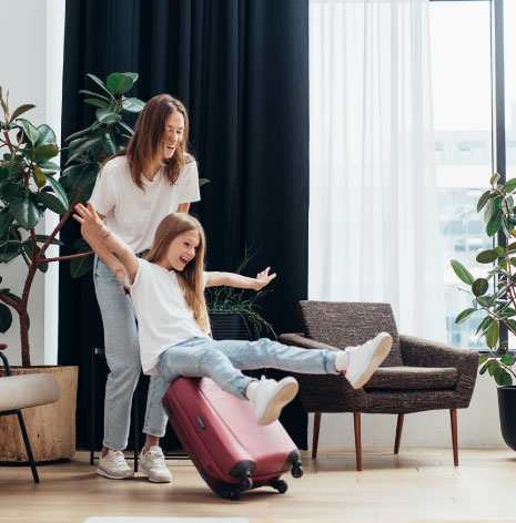 A mother and daughter playing with a suitcase in a modern living room